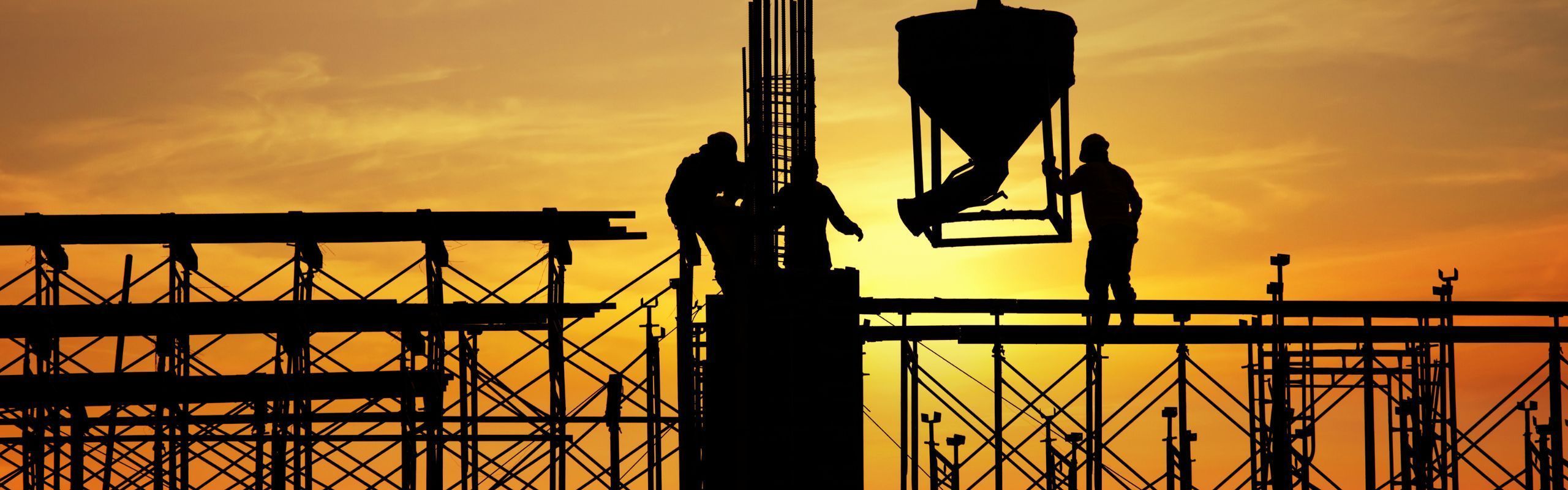 Image of construction workers on equipment against a sunset