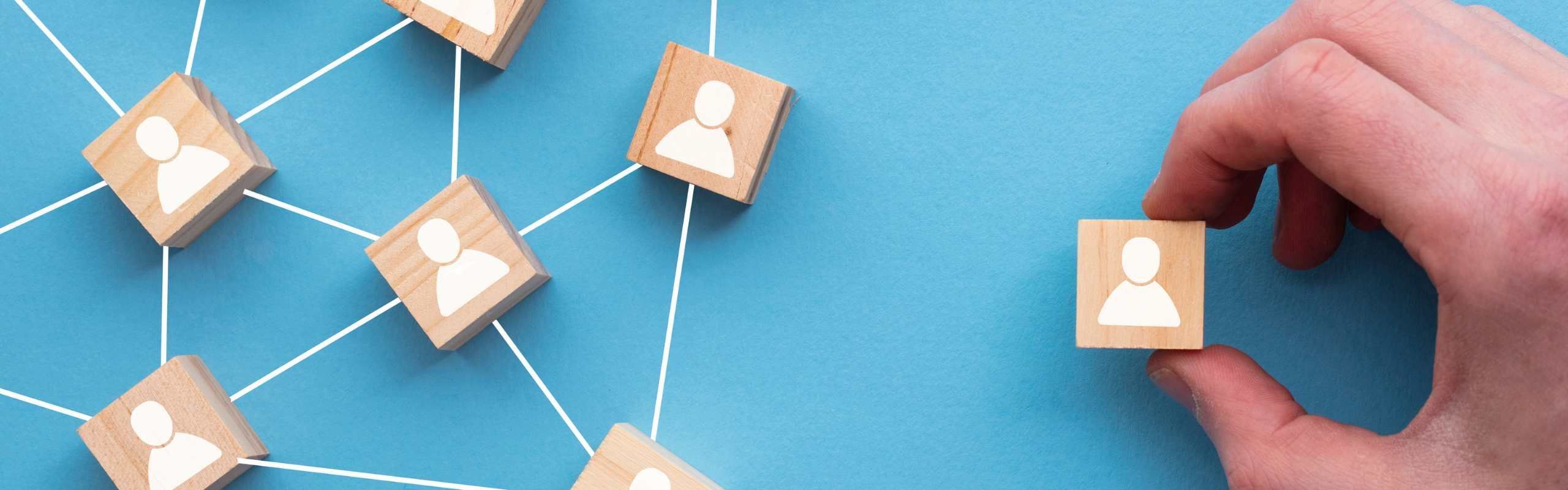 Graphic displaying wooden blocks with people icons against a blue background with a hand moving one wooden block away