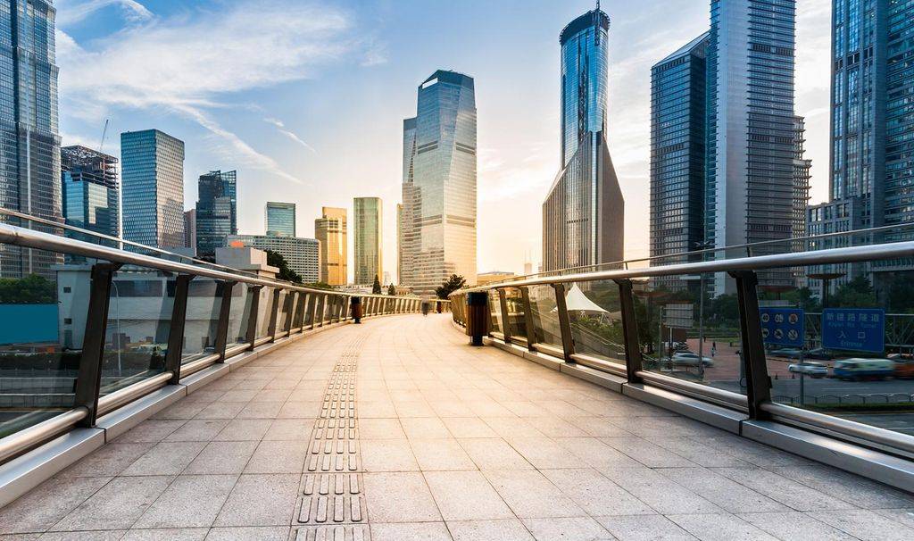 Pedestrian pathway between skyscrapers and sun shining