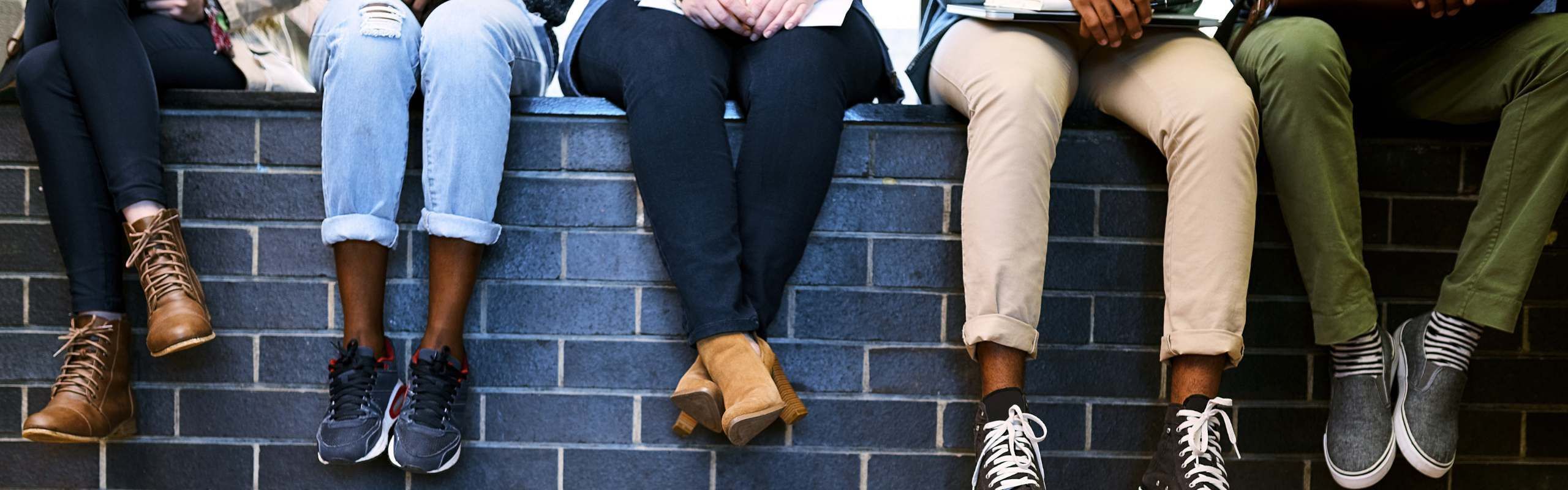 Students sitting on a wall outside of university