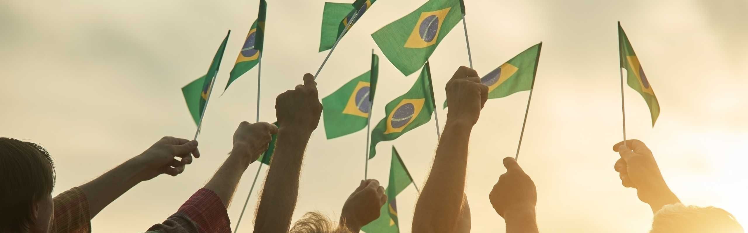 Hands holding Brazilian flags in the air