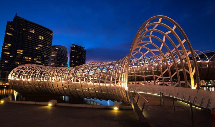 Pedestrian bridge over water at night with white webbed covering