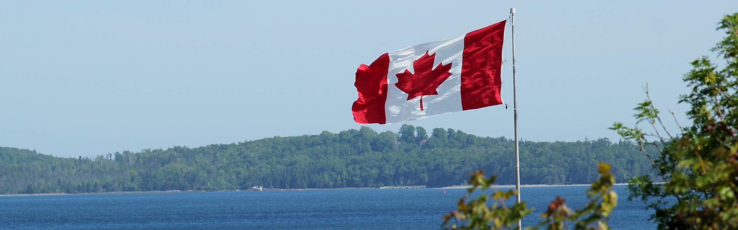 Canada flag over scenic background with lake and mountains